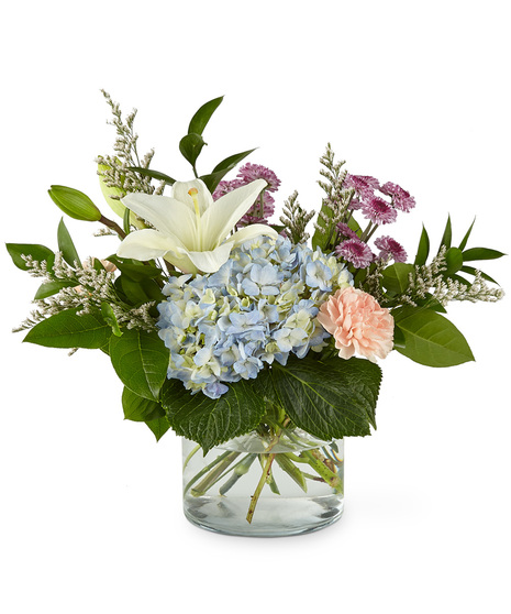 Mixed bouquet of flowers in a glass vase including hydrangea