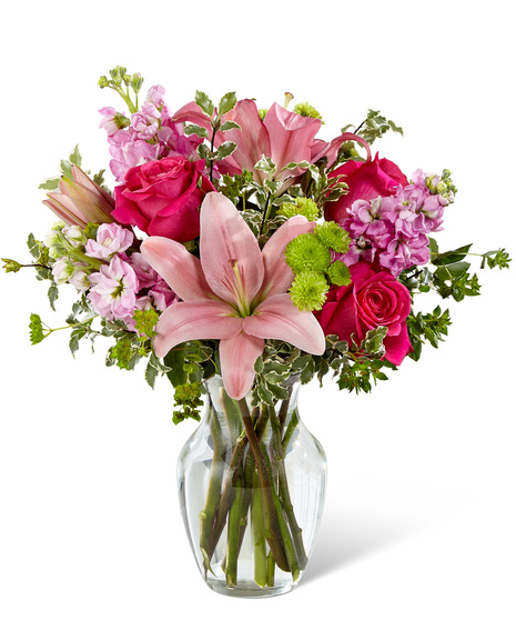 Pink flowers in a glass vase including lilies, roses and stock