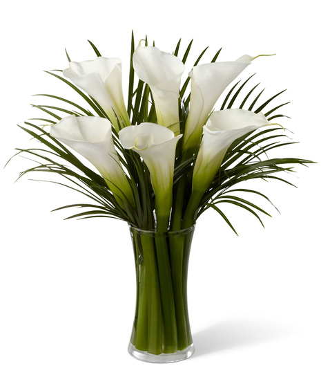 White calla lilies with special greens in a glass vase