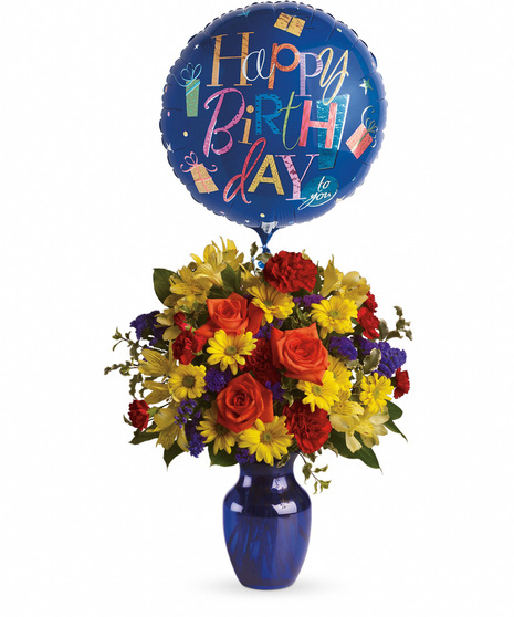 Vibrant flowers in a blue vase with birthday balloon