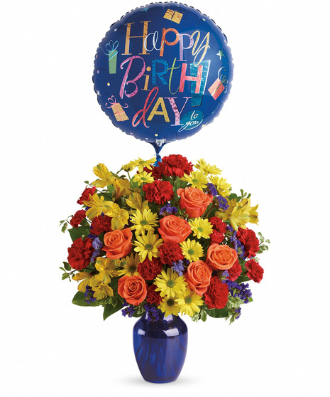 Vibrant flowers in a blue vase with birthday balloon