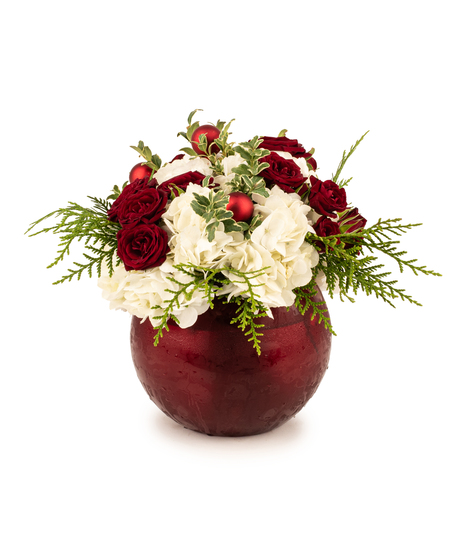 All-around Christmas centerpiece with hydrangeas, spray roses, red ornaments, and greens in an orb vase