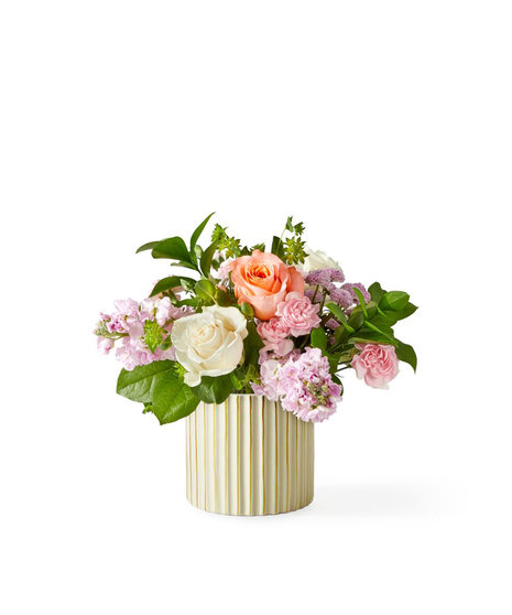 soft blush garden flower arrangement with roses stock and seasonal blooms in a modern ribbed vase