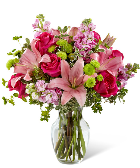 Pink flowers in a glass vase including lilies, roses and stock