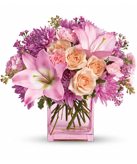Pink and peach flowers arranged in a pink cube vase