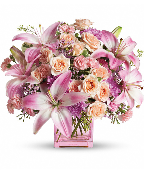 Pink and peach flowers arranged in a pink cube vase