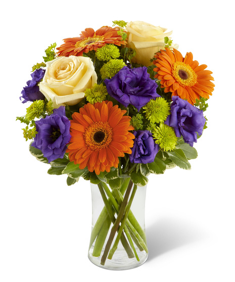 Orange, cream and purple flowers in a glass vase