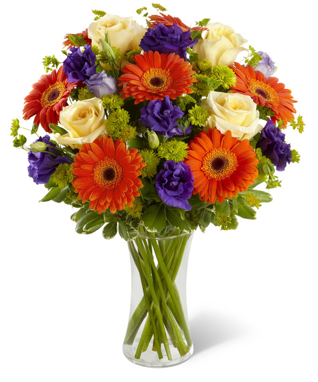 Orange, cream and purple flowers in a glass vase