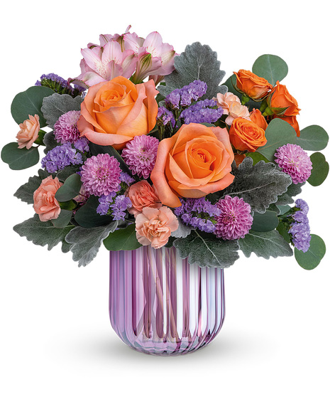 Spring flowers in orange and peach delivered in a lavender vase