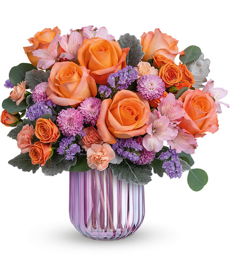 Spring flowers in orange and peach delivered in a lavender vase