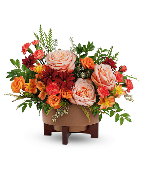 Copper Celebration Centerpiece with peach roses, orange spray roses, alstroemeria, carnations, and mums in a copper planter with wooden stand.