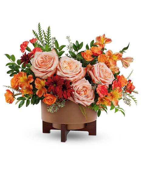 Copper Celebration Centerpiece with peach roses, orange spray roses, alstroemeria, carnations, and mums in a copper planter with wooden stand.