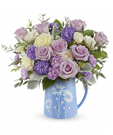 Daisy Haze Bouquet with lavender roses, pastel flowers, and greenery arranged in a blue pitcher with white daisy design