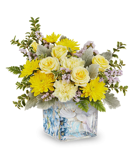 Yellow spring flower arrangement in decorative glass cube with dove and floral design.