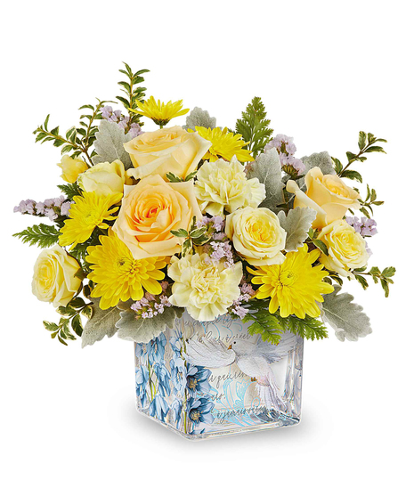 Yellow spring flower arrangement in decorative glass cube with dove and floral design.
