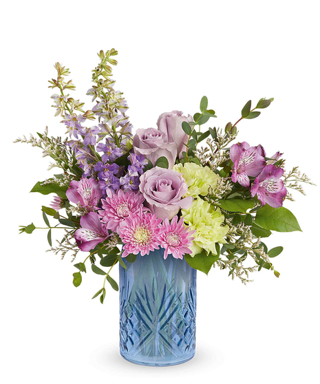 garden whimsy bouquet with lavender roses, pink flowers and green carnations in a blue glass vase