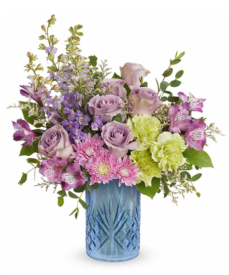 garden whimsy bouquet with lavender roses, pink flowers and green carnations in a blue glass vase