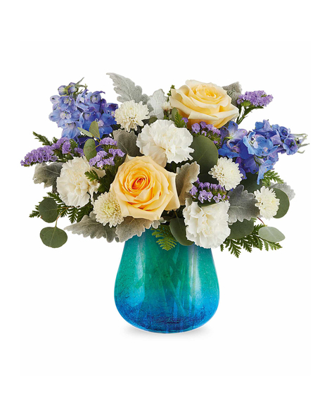Yellow and blue spring flower arrangement in turquoise crackled glass vase