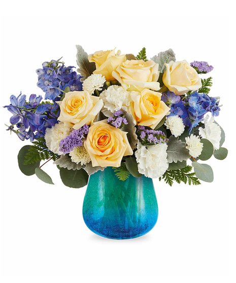 Yellow and blue spring flower arrangement in turquoise crackled glass vase