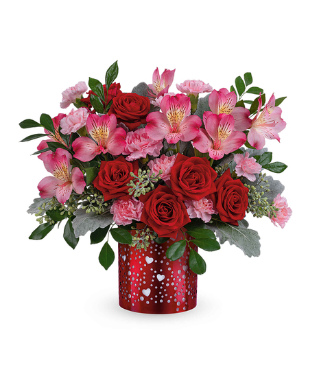 Romantic red and pink flower arrangement with roses, alstroemeria, and carnations displayed in a red metal lantern with heart cutouts