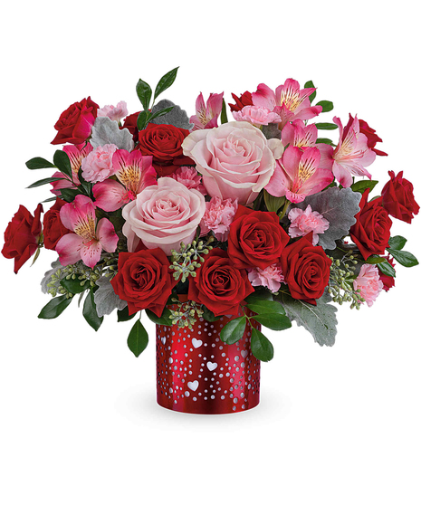 Romantic red and pink flower arrangement with roses, alstroemeria, and carnations displayed in a red metal lantern with heart cutouts