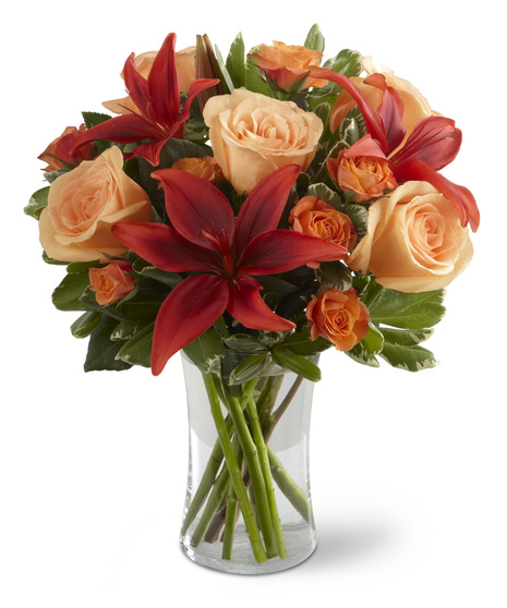 Peach, orange and red flowers in a glass vase