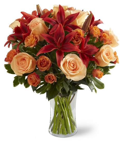 Peach, orange and red flowers in a glass vase