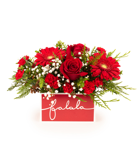 All-around Christmas flower arrangement with roses, gerberas, carnations, and greens in a red 